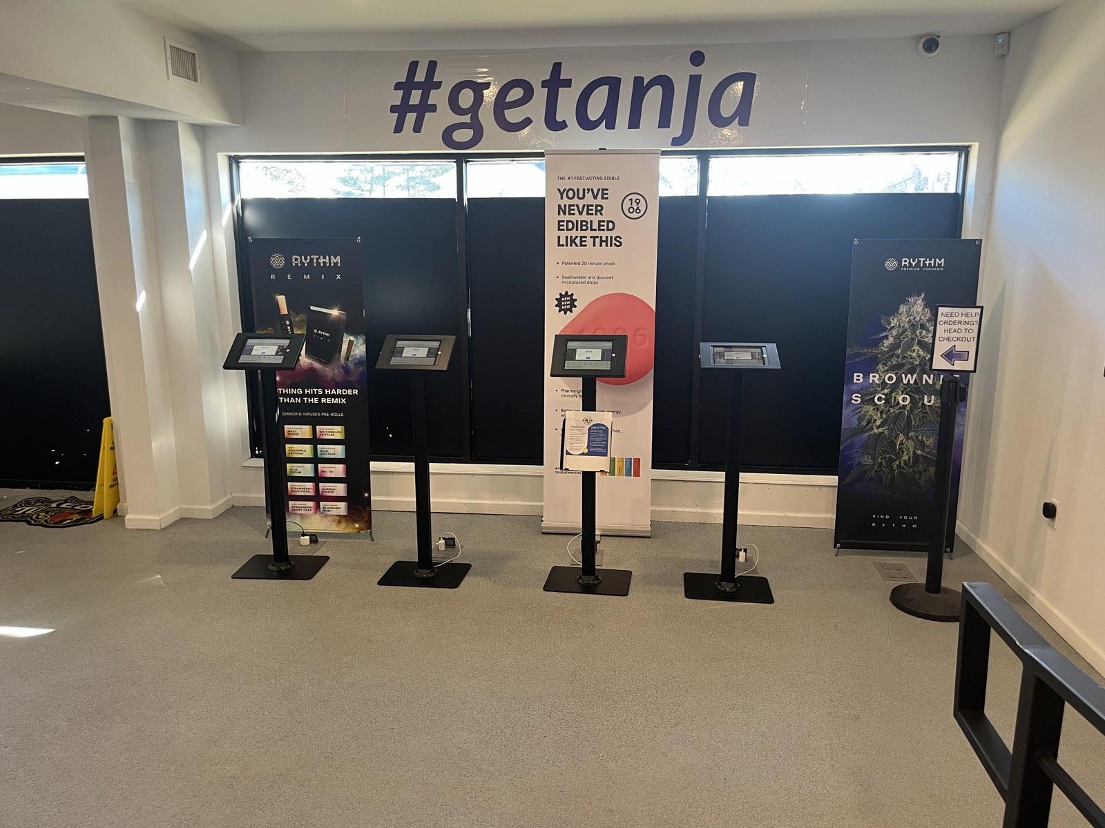 Self-order kiosks under the #getanja wall inside the ANJA dispensary